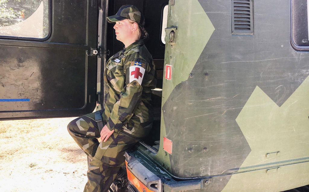En kvinnlig militär sjukvårdare bredvid en lastbil.