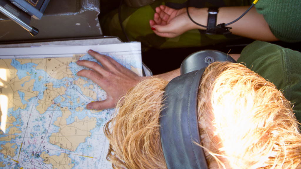 En soldat tittar ned på en karta med hörlurar på sig.