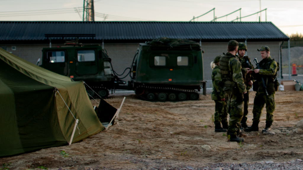 Några hemvärnssoldater står och pratar med varandra bredvid ett tält.