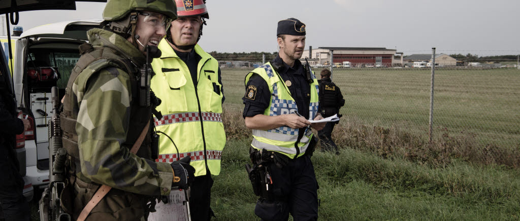 Civil räddningstjänst, polis, ambulans och personal från Försvarsmakten hjälps åt för att ta hand om skadade på Visby flygplats. Scenariot är att fientligt flyg fällt bomber mot svenskt luftvärn men träffat en civil marknadplats som låg i närheten. Första larmningen gick via 112 och ett stort antal myndigheter samordnade räddningsinsatsen.