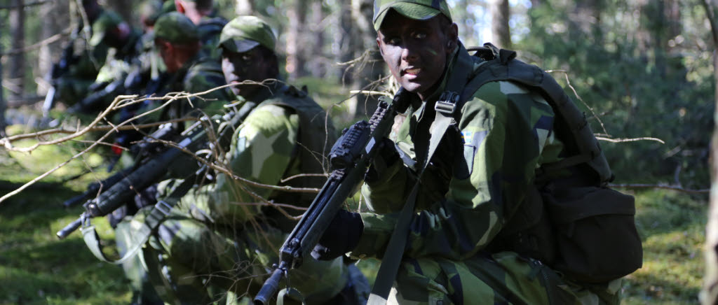 Flera krigsmålade soldater är beredda med sina vapen. 