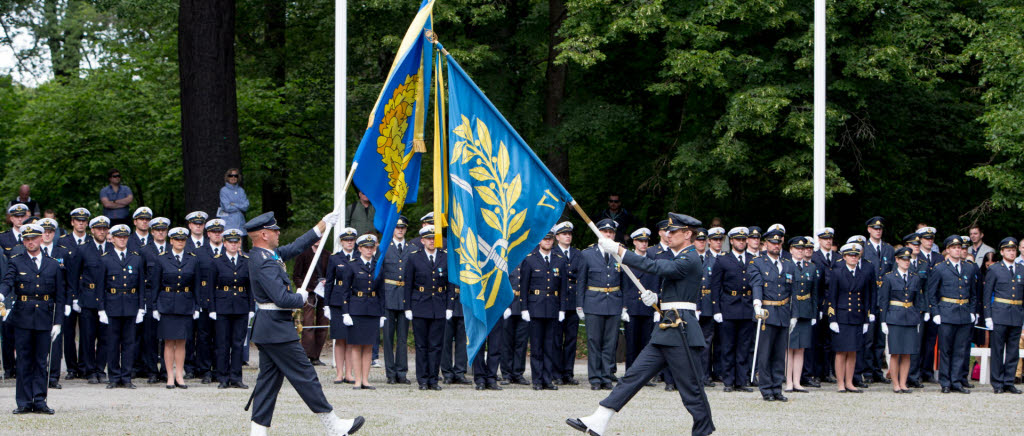 Militärhögskolan och Försvarshögskolans fanor paraderas framför kadetter vid examensceremoni. (Arkivbild)