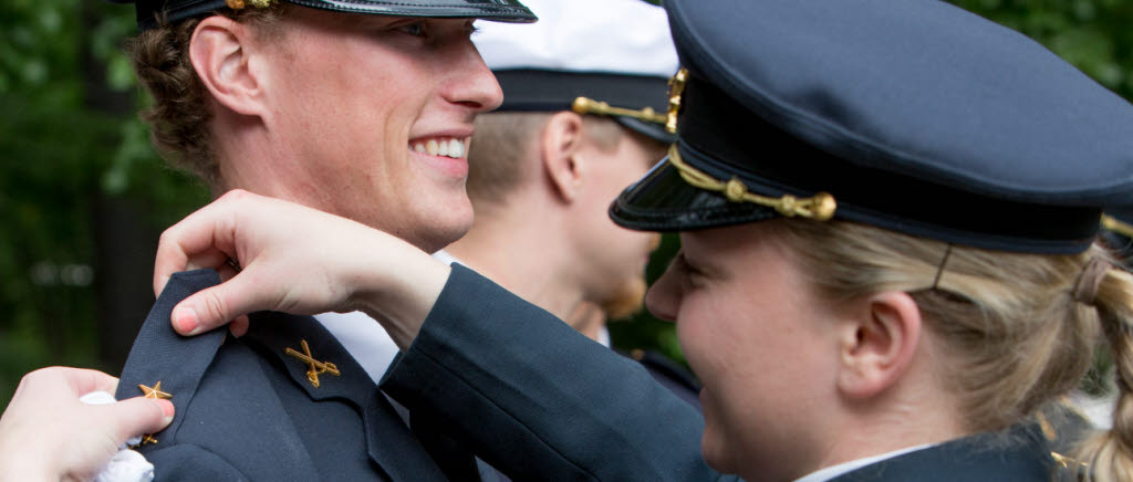 Kadetterna byter gradbeteckningar åt varandra. Här får en armékadett hjälp att avlägsna kadettvinklar och fästa fänriksstjärna.