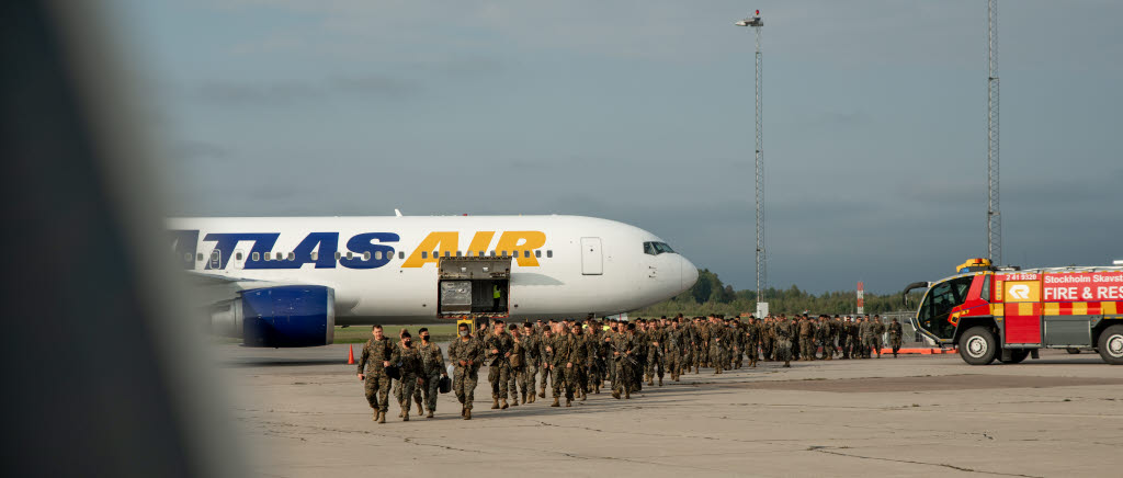 Soldater bredvid ett flygplan på en flygplats.