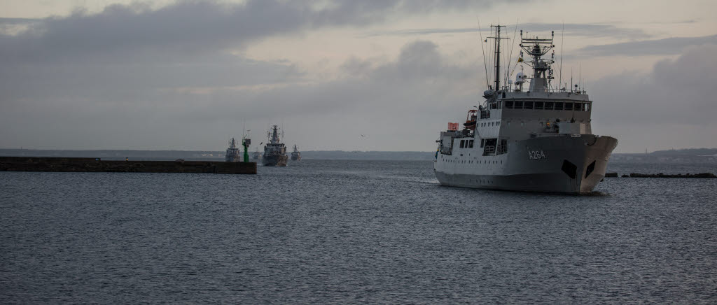 HMS Trossö med minjaktsfartyg i bakgrunden anlöper in mot Tallinn hamn. 