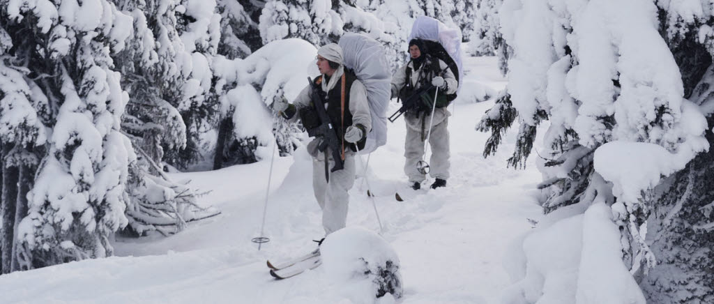 Jägaraspiranter under framryckning med skidor i tät skog.