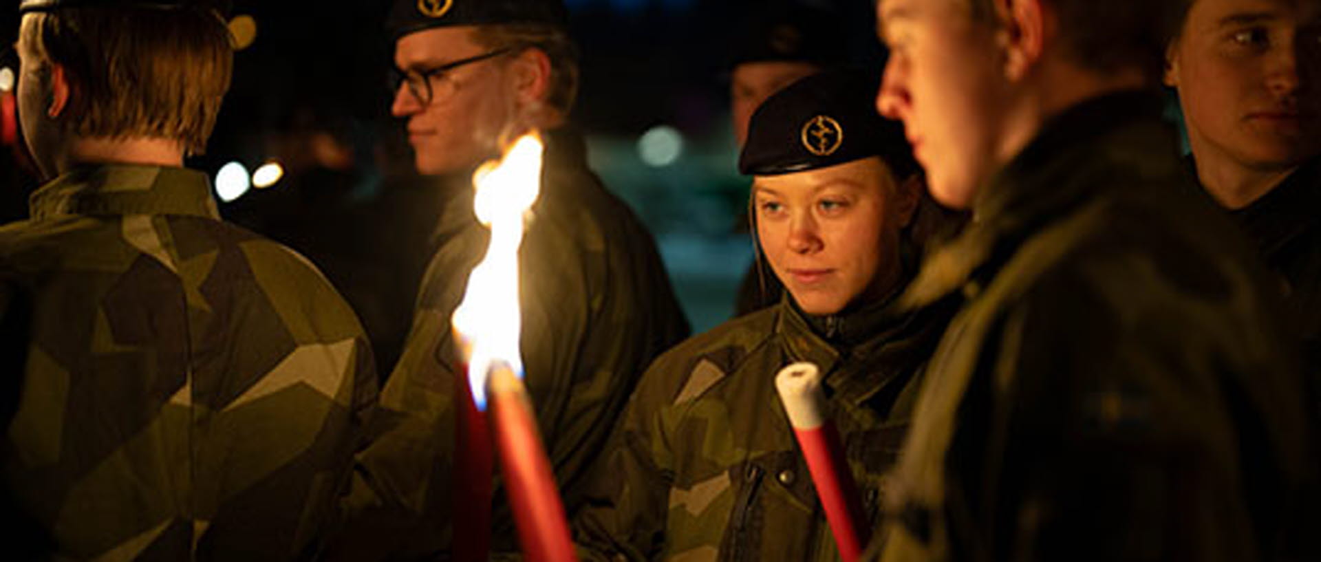 Facklor lyser upp ansiktena på unga soldater i mörk kväll