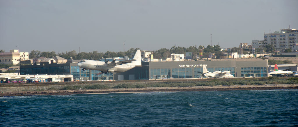 En C-130 Hercules lyfter från Aden Abdulle Airport, Mogadishus internationella flygplats, sett från en svensk stridsbåt. Som en del av EU Naval Force beredduppgift (secondary support task) levererar fartyget HNLMS Johan de Witt två fordon till EUCAP NESTOR. Detta sker genom en logistikoperation mot flygplatsen i Mogadishu. Svenska stridsbåtar agerar platformar för spaning och undersökning av stranden under den förberedande fasen och som närskydd för landstigande delar via den holländska LCU:n (Landing Craft Utility) under genomförandefasen.