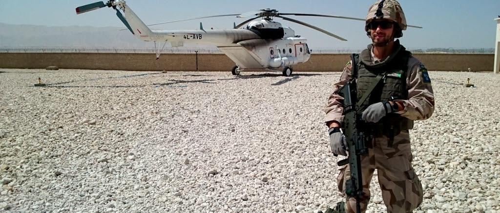 Fidde stående på marken framför en helikopter i Afghanistan