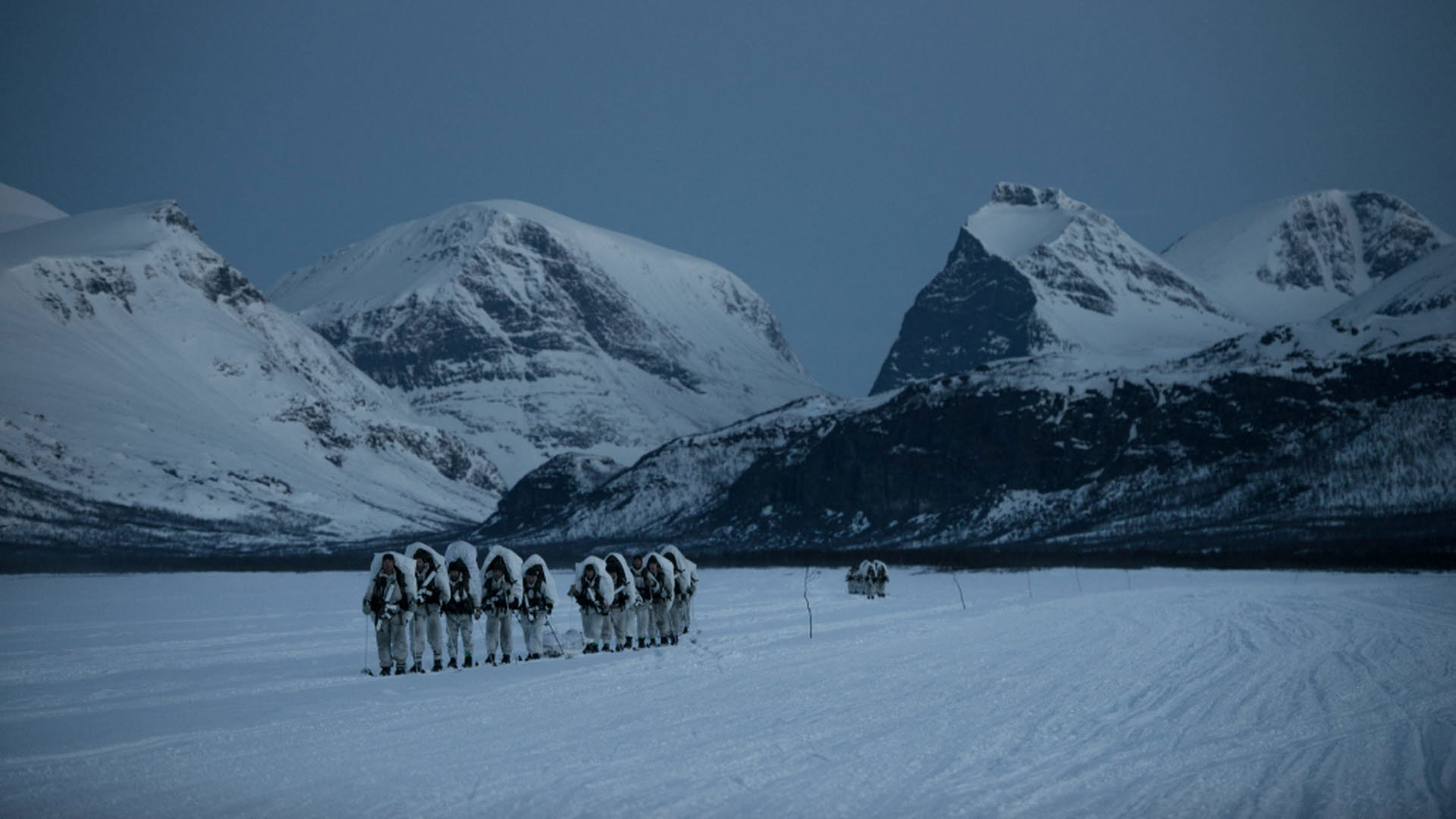 Skidmarsch över frusen sjö med mörker som skydd.